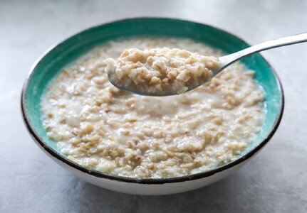 spoon-held-over-bowl-of-cooked-oats-porridge.jpg