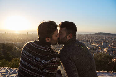 gay-boyfriends-kissing-while-sitting-on-observation-point-bunkers-del-carmel-barcelona-spain-V...jpg