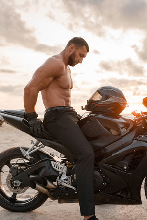 215586575-ripped-man-with-muscular-torso-on-his-black-sports-motorcycle-on-desolate-beach.jpg