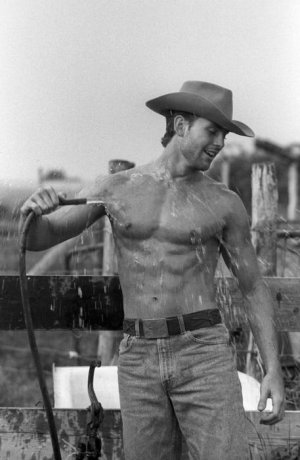 shirtless-cowboy-cooling-off-with-water-from-a-hosse-on-a-ranch.jpg