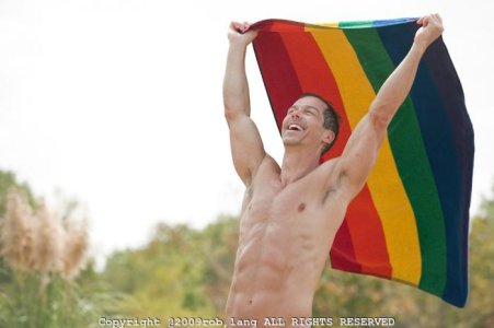 shirtless-man-smiling-and-waving-a-rainbow-towel.jpg